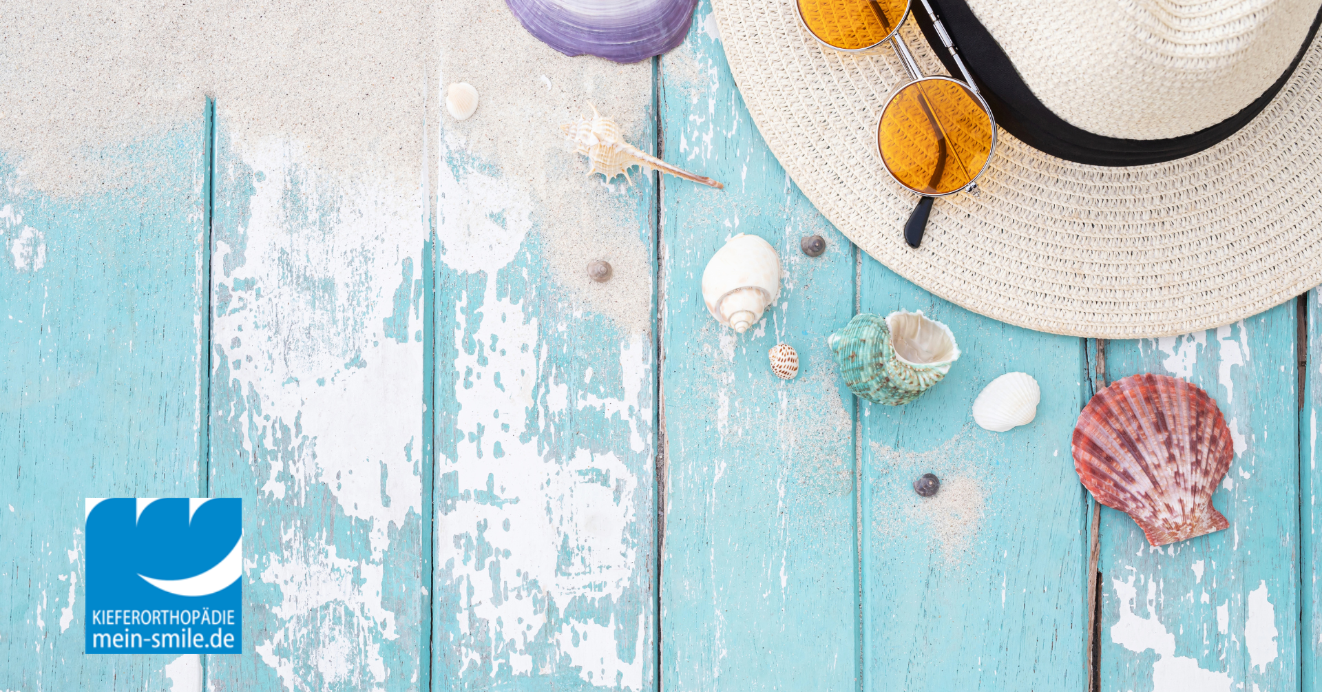 Sommeraccessoires mit Muscheln auf einem türkisen Holztisch.